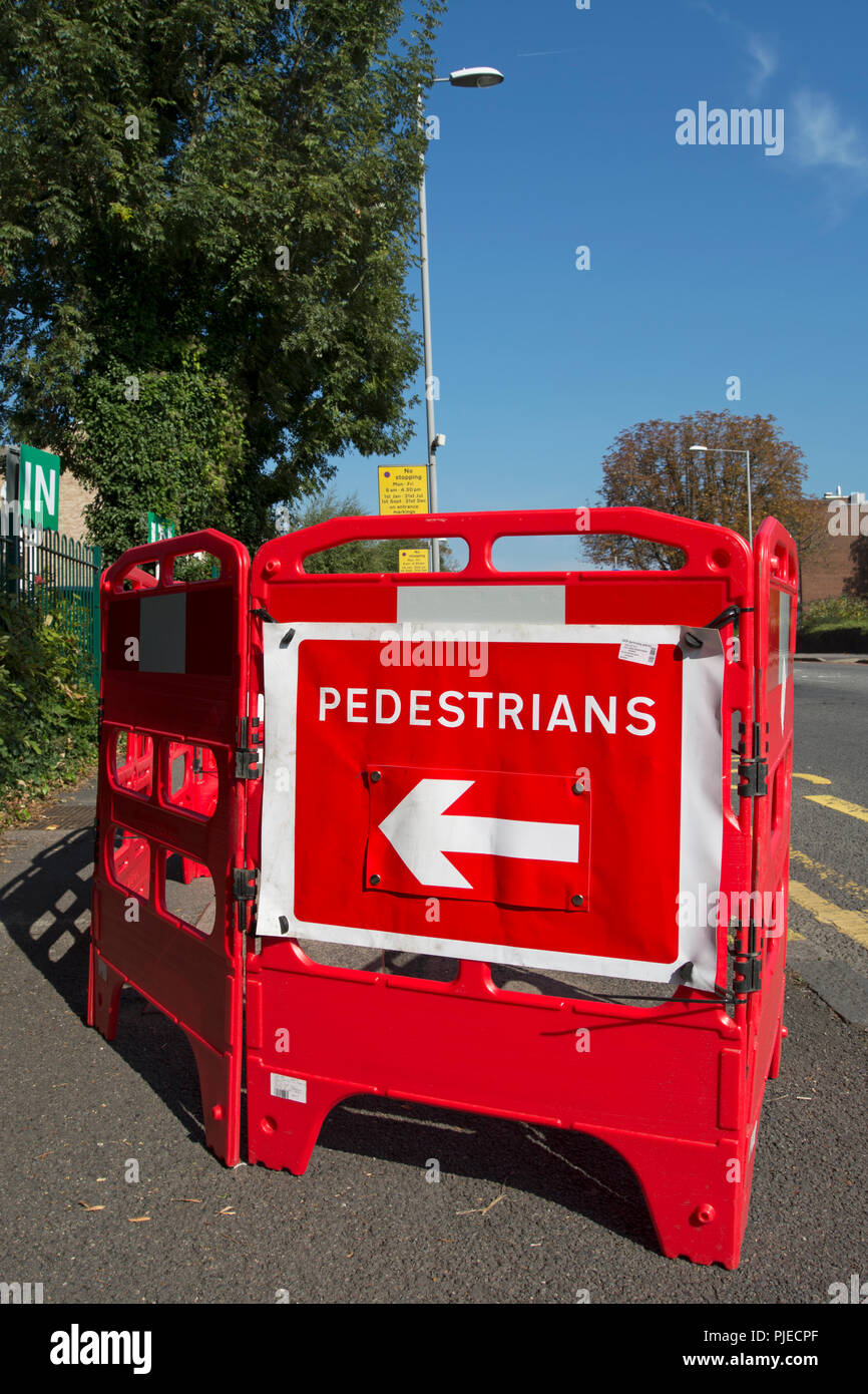 red plastic barriers and red and white sign indicating pedestrians should walk to the left at footway works in surbiton, surrey, england Stock Photo