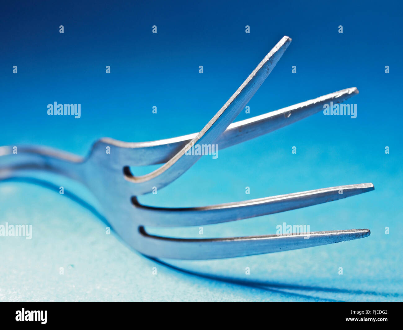 broken fork macro abstract object still life blue background cocnept Stock Photo