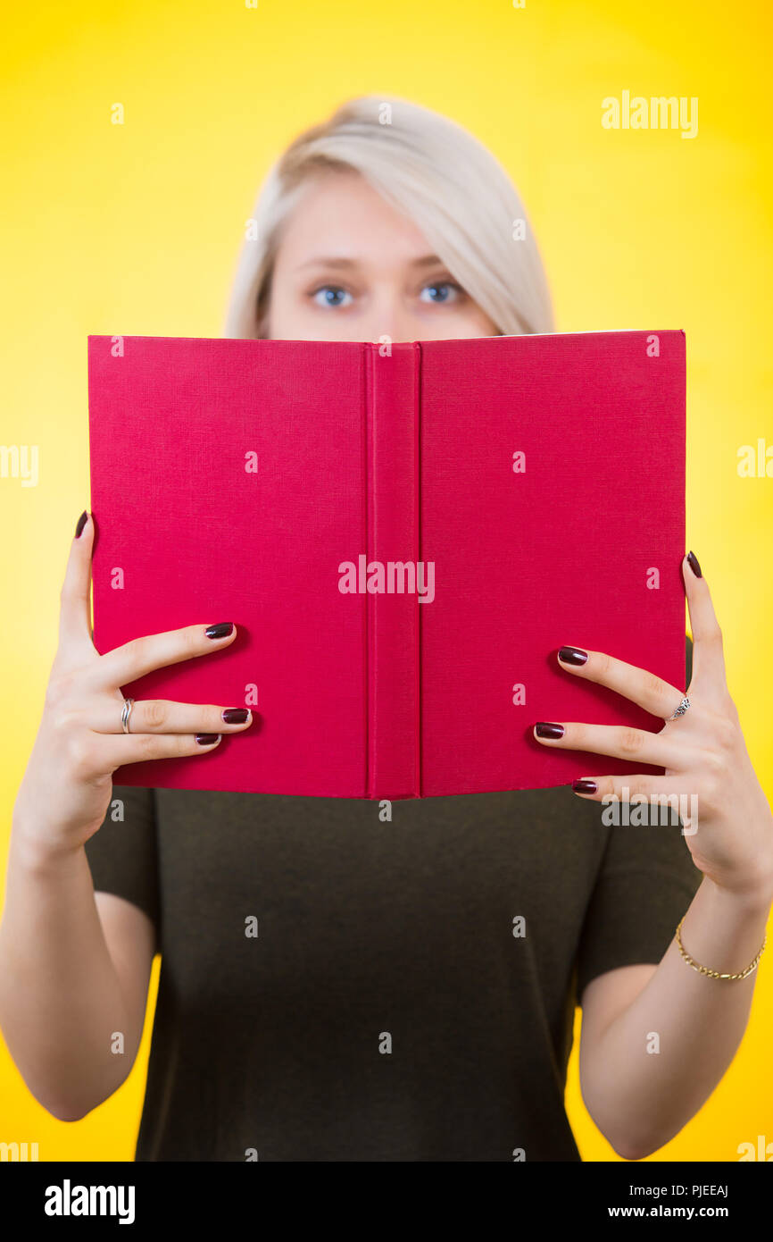 Young woman covering half face with a opened red book. Author ...