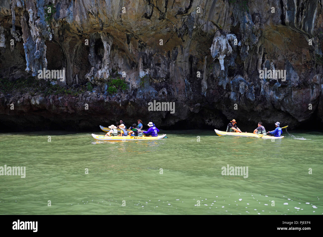 Tourists explore with the canoe eroded limestone rocks in the bay of Phang Nga, Thailand, Touristen erkunden mit dem Kanu erodierte Kalksteinfelsen in Stock Photo