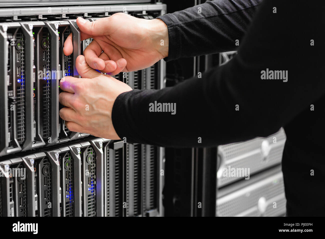 Male IT Engineer Replacing Blade Server In SAN At Datacenter Stock Photo