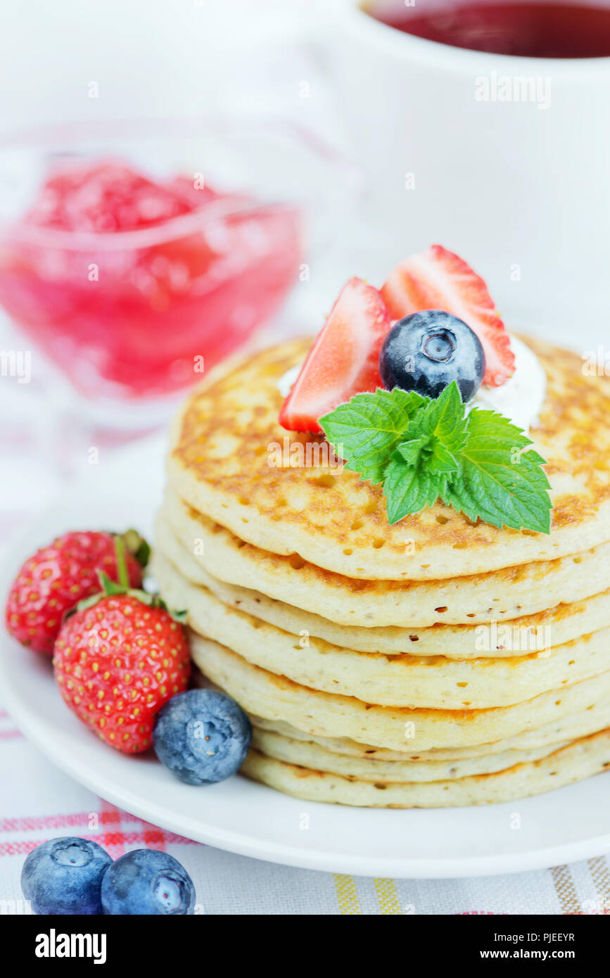 A stack of pancakes decorated with ripe raspberries, blueberries and sour cream close-up Stock Photo