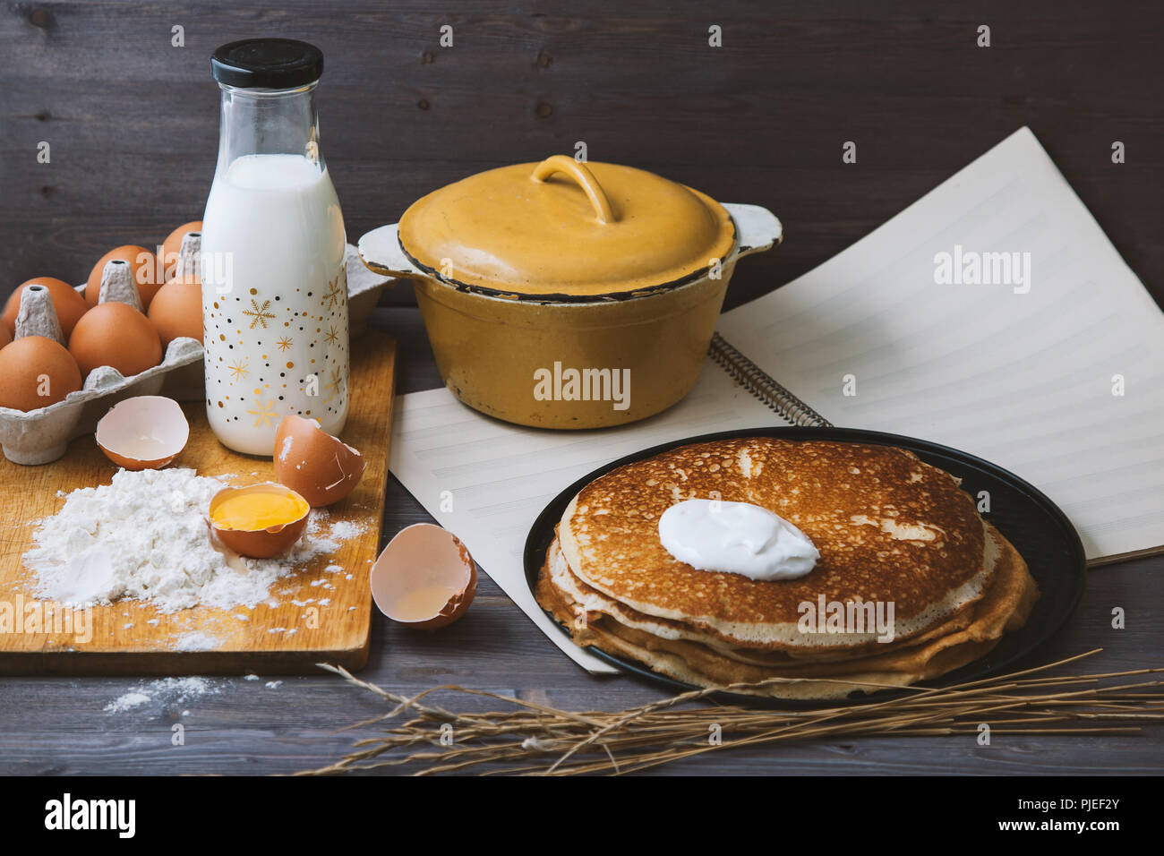 fresh, hot pancakes in a frying pan, eggs, milk, flour on a wooden