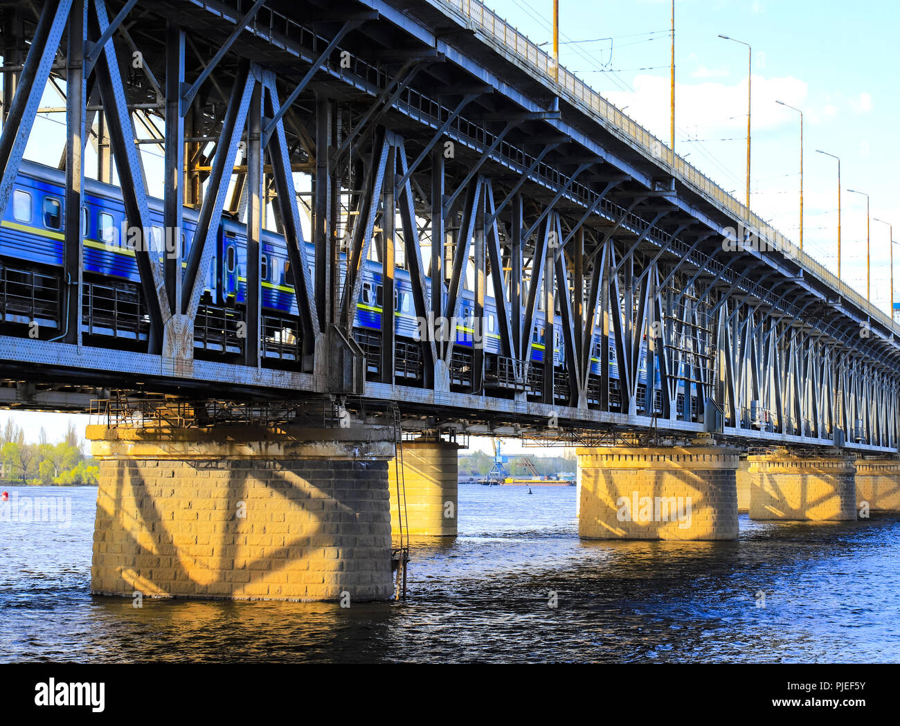 The passenger train travels along a two-level bridge and a railway across the Dnieper  River in the Dnipro city. Dnepropetrovsk, Dnepr),Ukraine Stock Photo