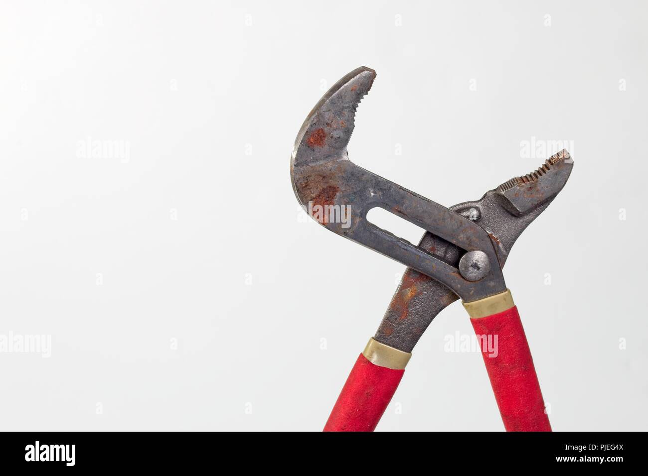 Rusty old Pipe Pliers with red rubber handles Stock Photo