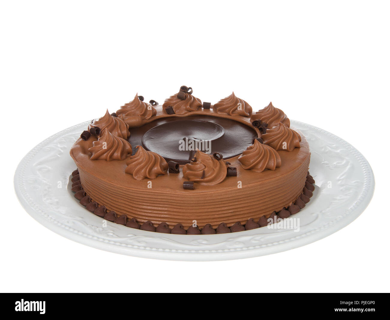 Home made chocolate cake with chocolate fudge on top on an off white porcelain plate isolated on white background. Stock Photo