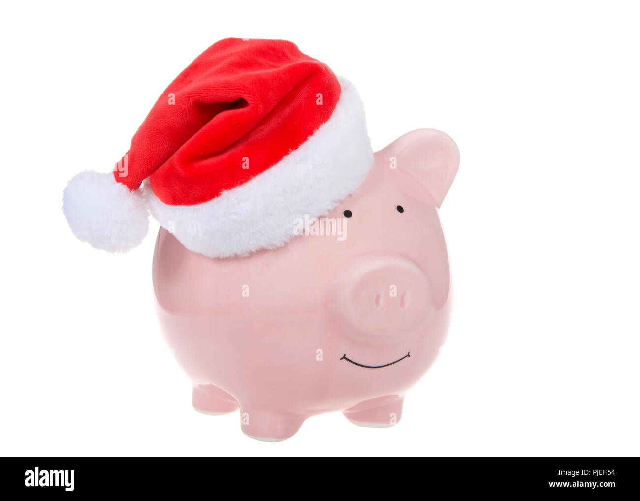 Pink piggy bank wearing a Santa hat smiling facing viewers right isolated on white. Stock Photo