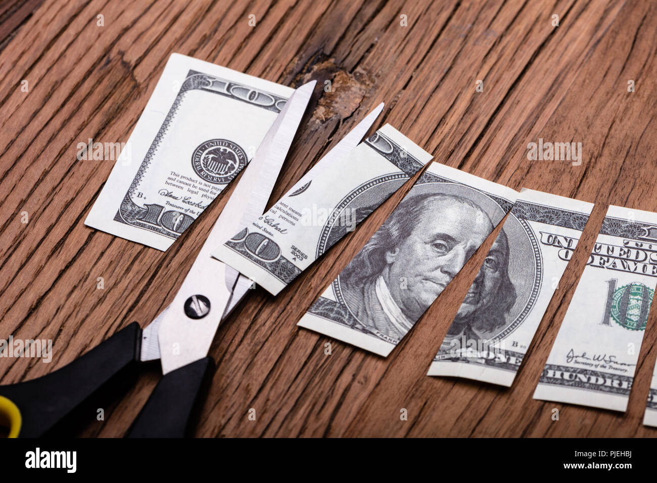 Cutted Dollar Banknote And Scissor On Wooden Table Stock Photo
