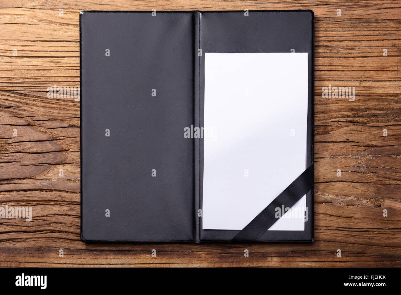 Overhead View Of Blank Empty White Paper In Black Leather Folder On Wooden Table Stock Photo
