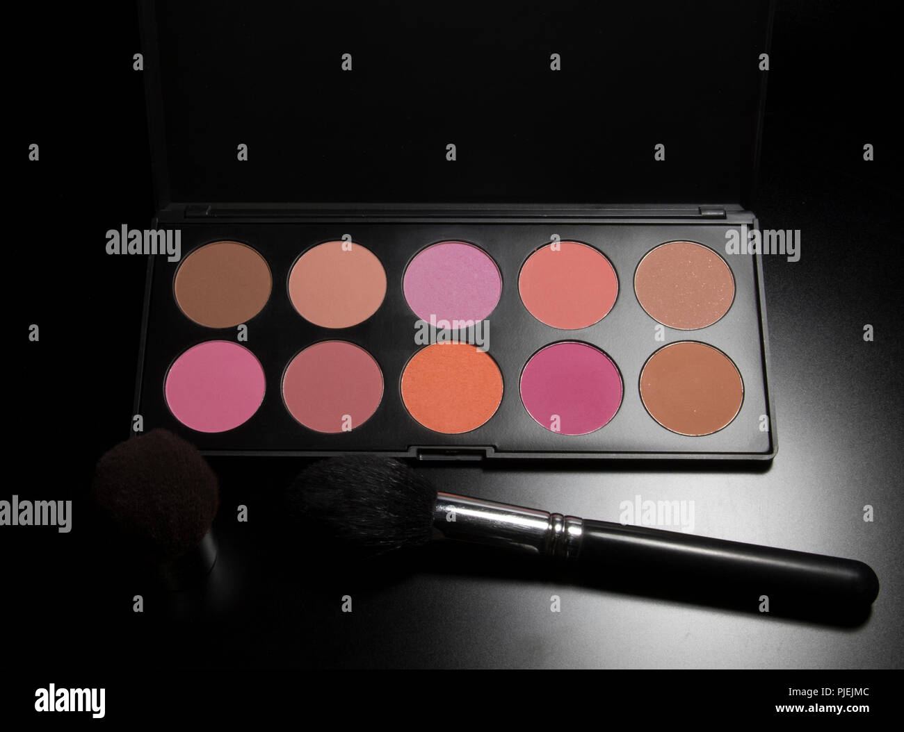 Blush makeup pallet container with brush on black background