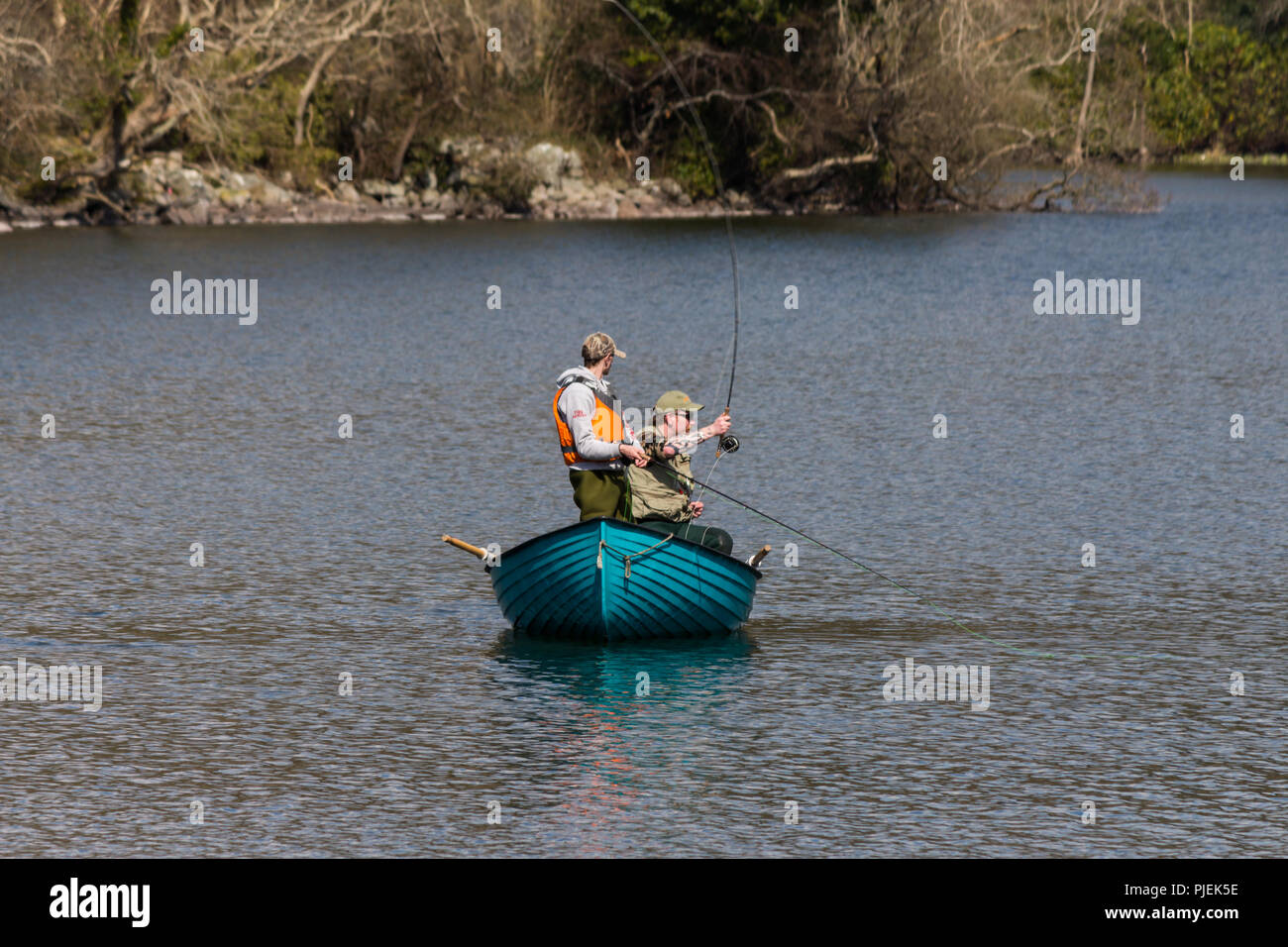 Fishermen casting from fishing boat on a lake Stock Photo