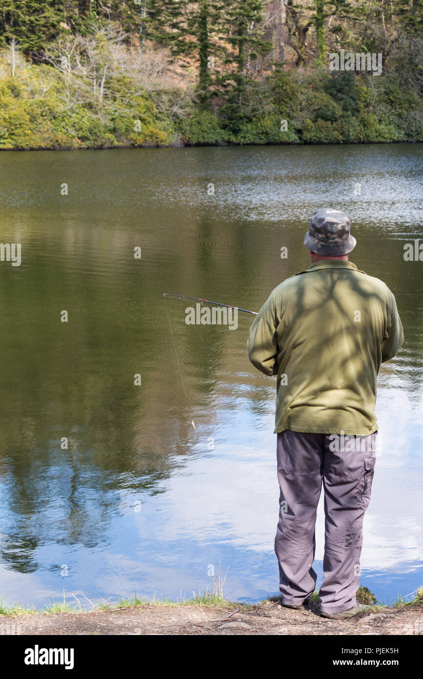 Man fishing at lakeside shore Stock Photo