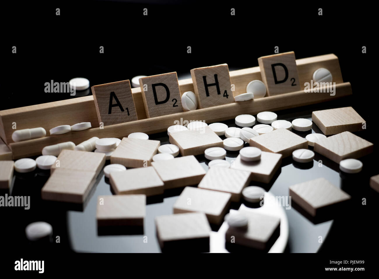ADHD spelled in Scrabble text with white prescription pills spilled on