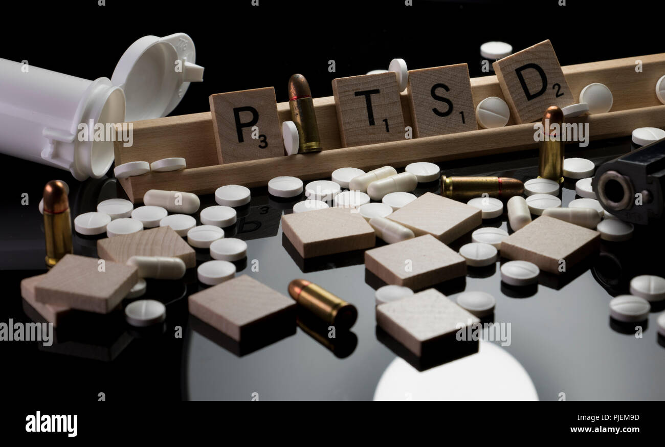 PTSD in Scrabble text with pills, bullets and hand gun. Concept of Post