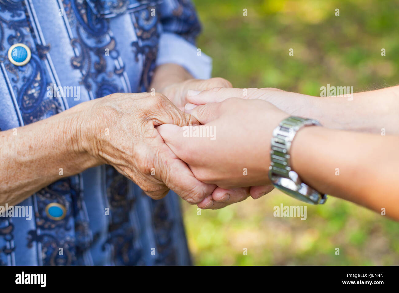Close up picture of young woman holding her senior grandmother's wrinkled hands Stock Photo
