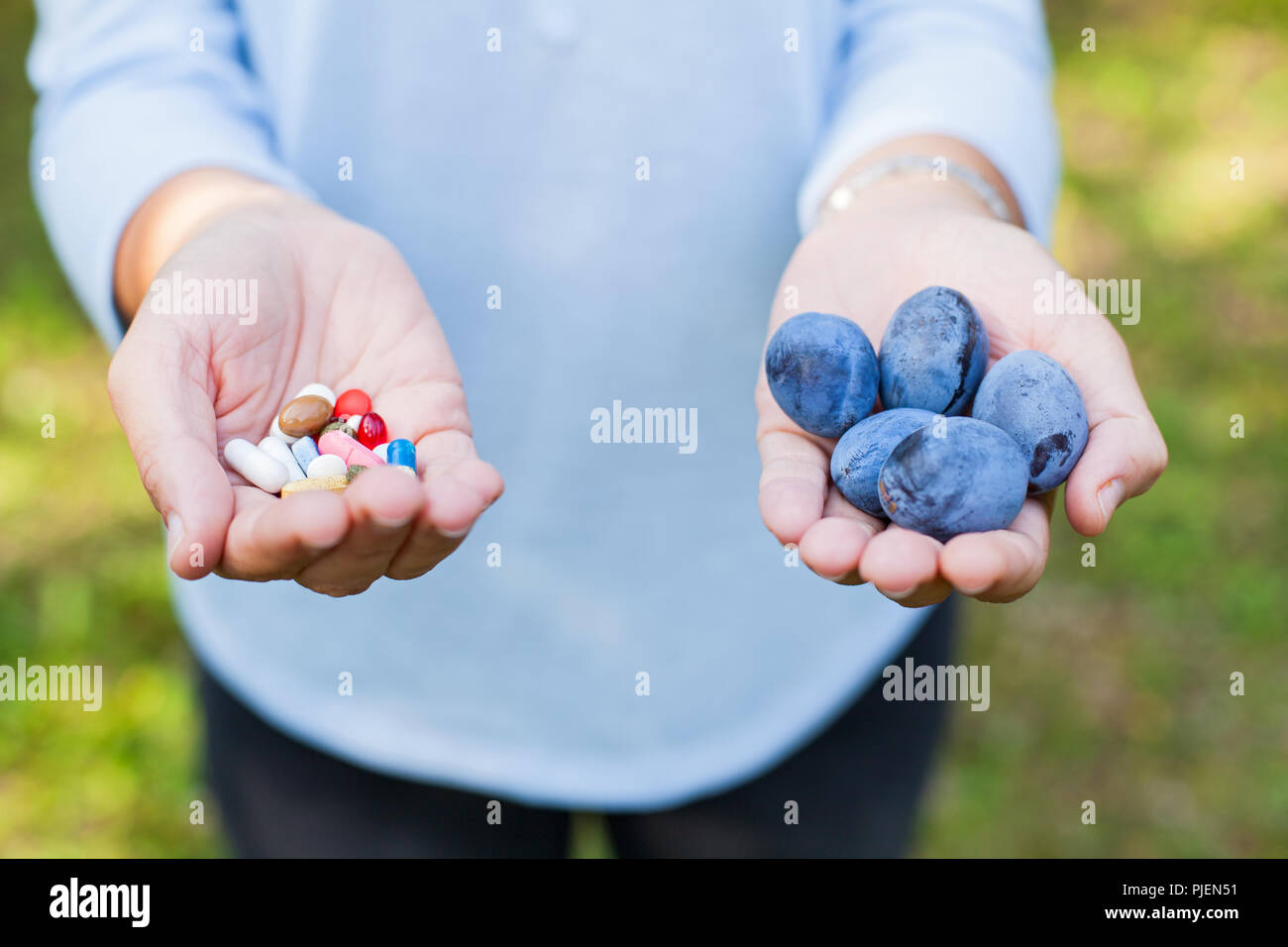 Close up picture of female holding ripe plums and medical drugs in her