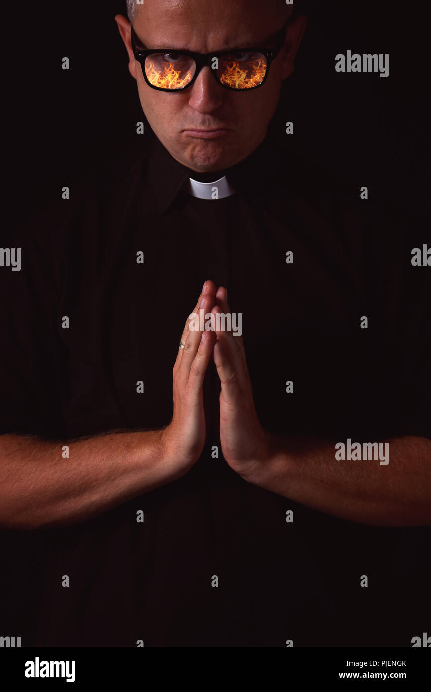 priest with a reflection of fire in glasses Stock Photo