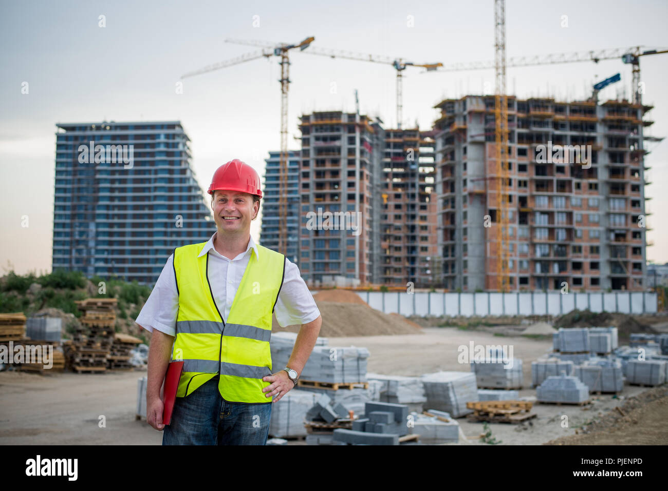 Engineer looking at camera on a construction site wearing reflective west working on housing project Stock Photo
