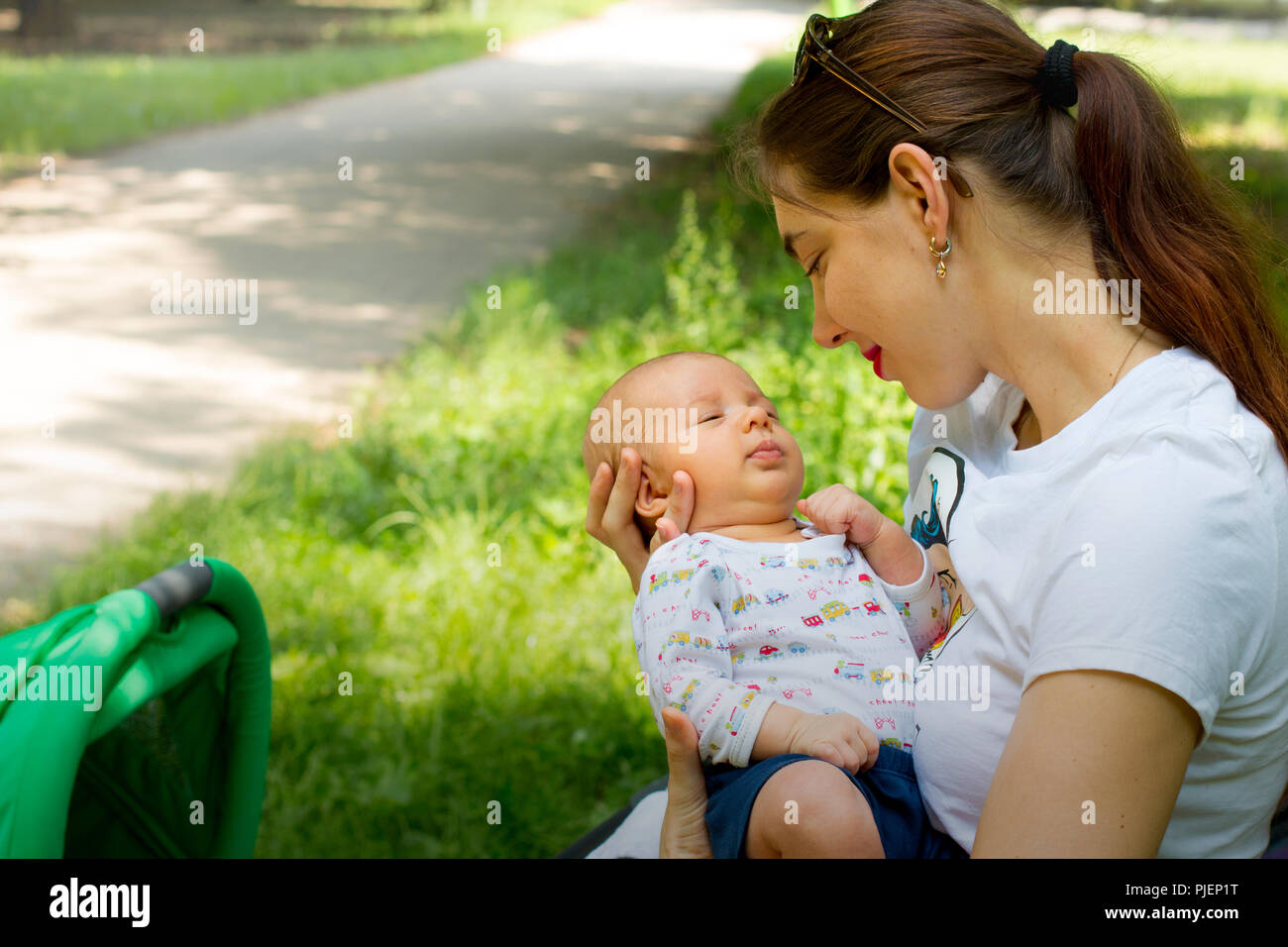 Mother and child, happy young woman is holding her cute baby in the hands, loving mother smiling and cuddling on her little newborn, maternity love Stock Photo
