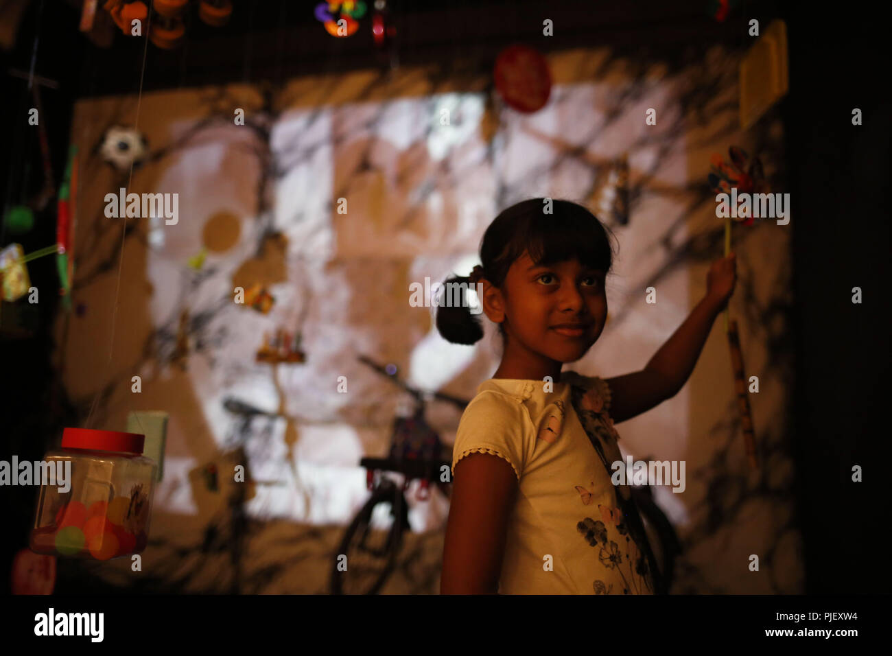 Dhaka, Bangladesh. 5th Sep, 2018. A child poses for a photo behind a painting at 18th Asian Art Biennale at Shilpakala Academy, a monthly long expiation open national gallery as first Asian Art biennale was held in Bangladesh in 1981. Credit: MD Mehedi Hasan/ZUMA Wire/Alamy Live News Stock Photo