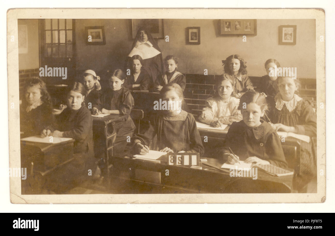 Edwardian postcard of junior school girls in classroom, sitting at their desks in a convent school, nun in class, circa 1910, U.K. Stock Photo