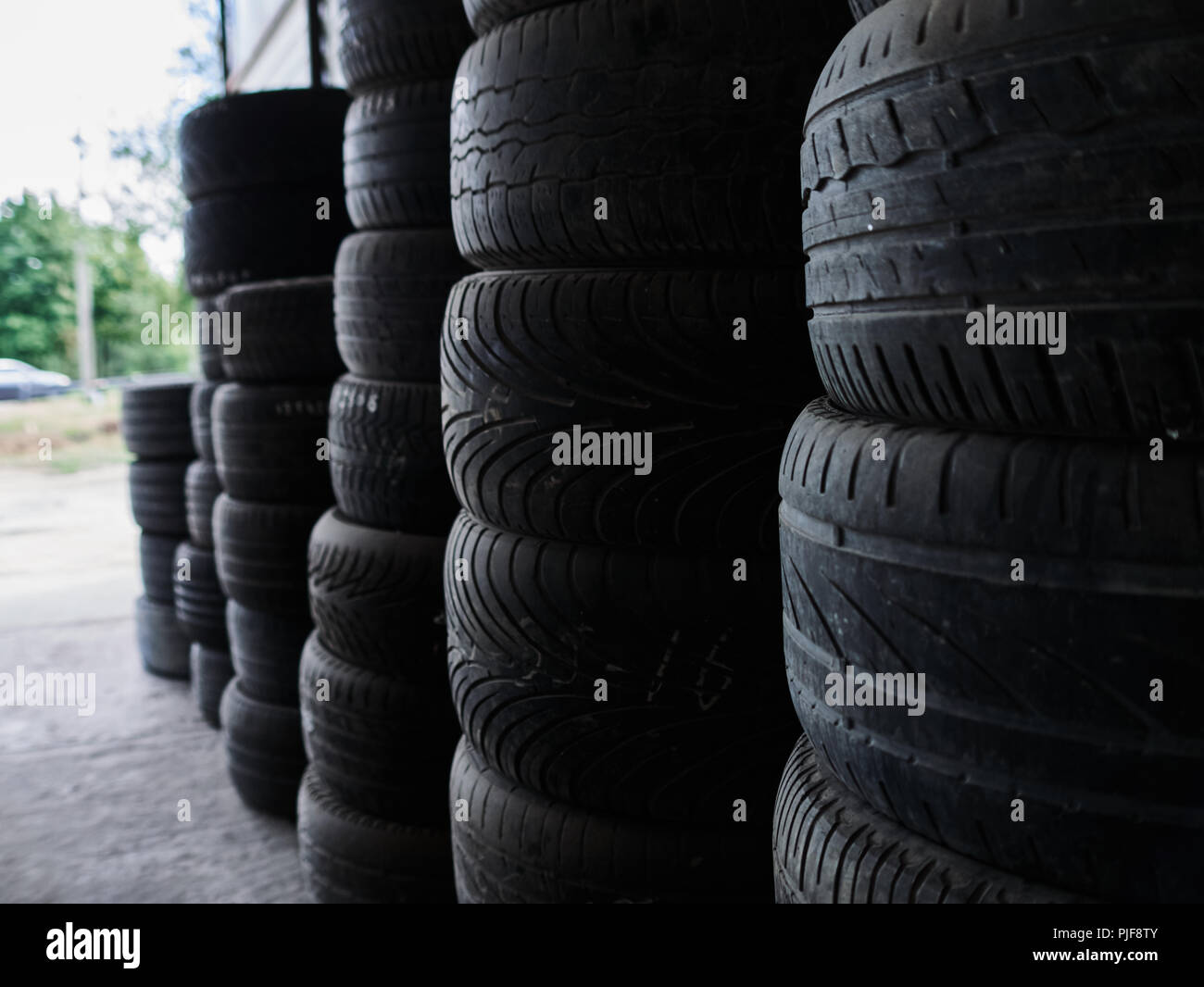 Used car tires stacked in piles at junkyard. Old wheels recycling and