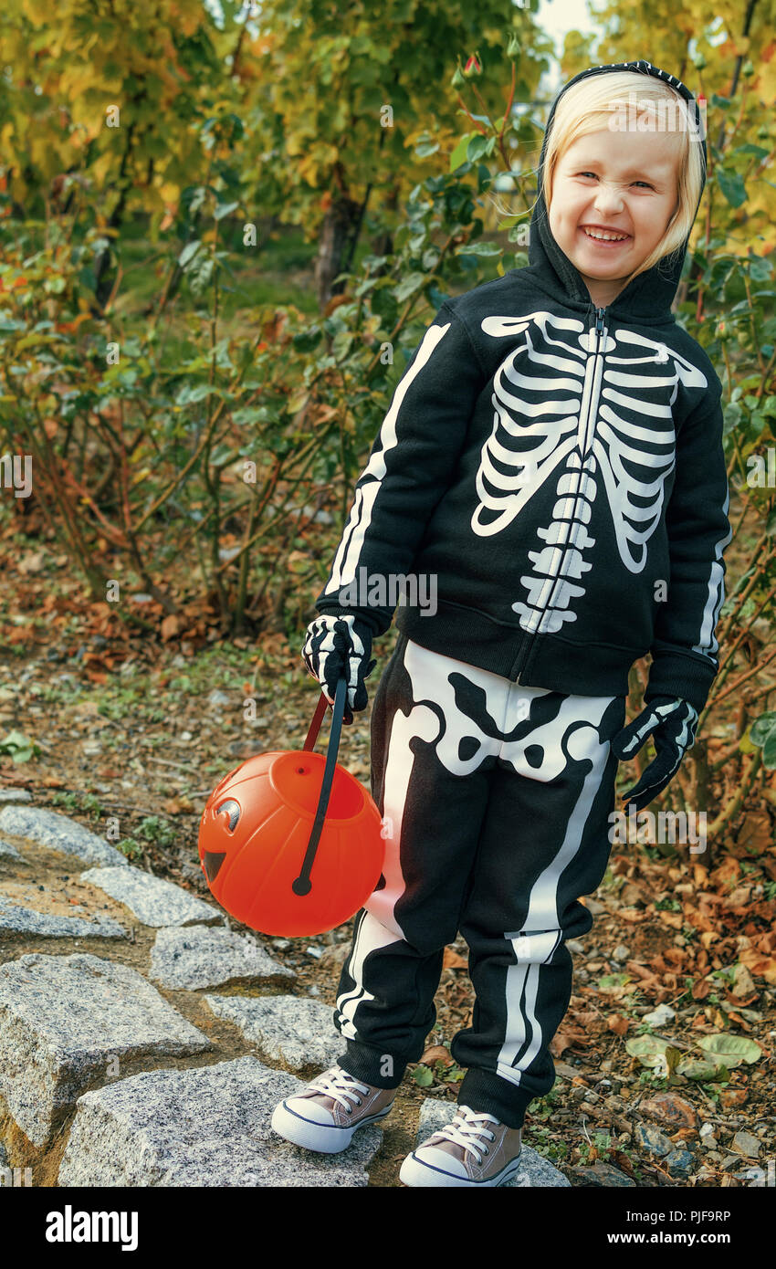 Trick or Treat. happy child wearing skeleton costume on Halloween outdoors  holding pumpkin Jack O'Lantern basket Stock Photo - Alamy