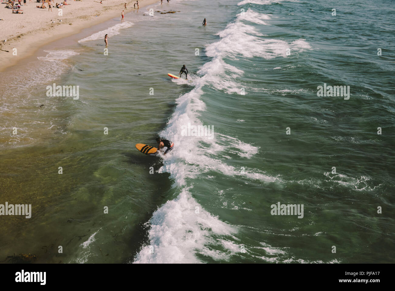 High view of surfers and swimmers in the ocean on a sunny day Stock Photo