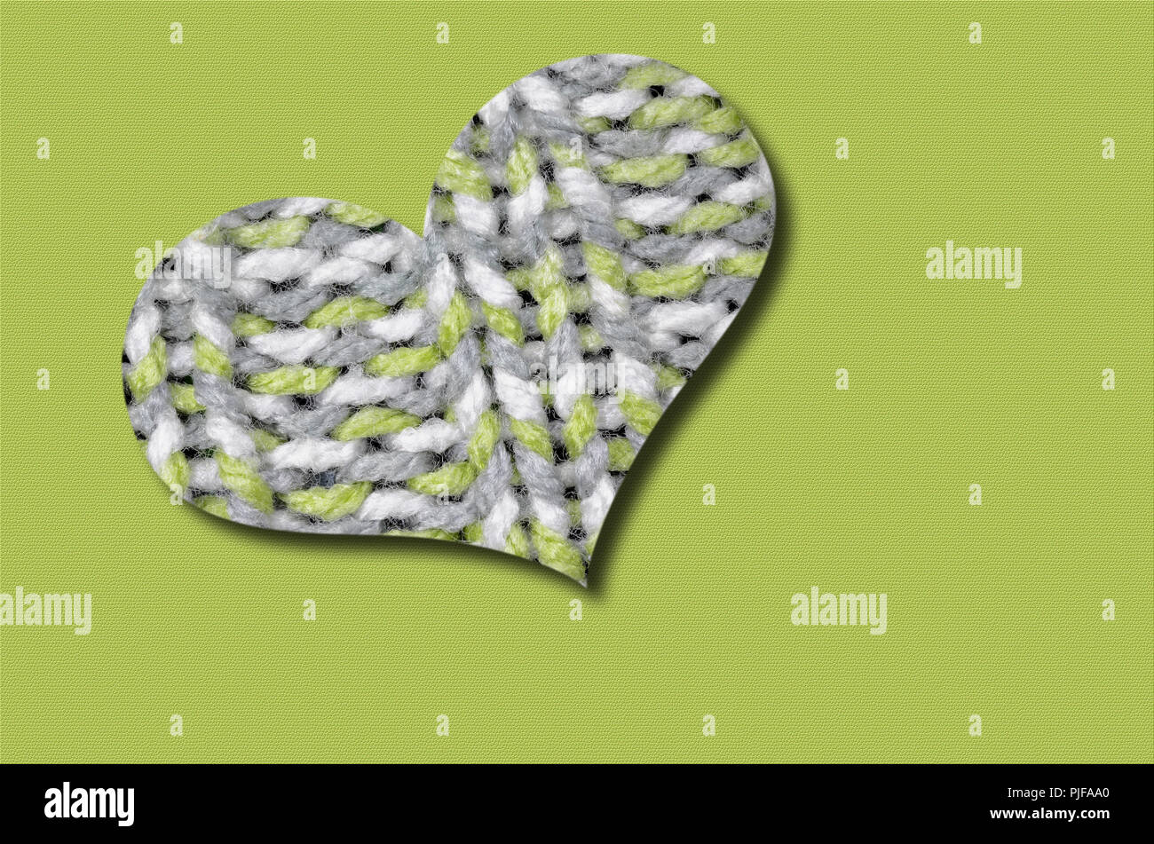 knitted heart, light green, gray and white, isolated on light green background Stock Photo