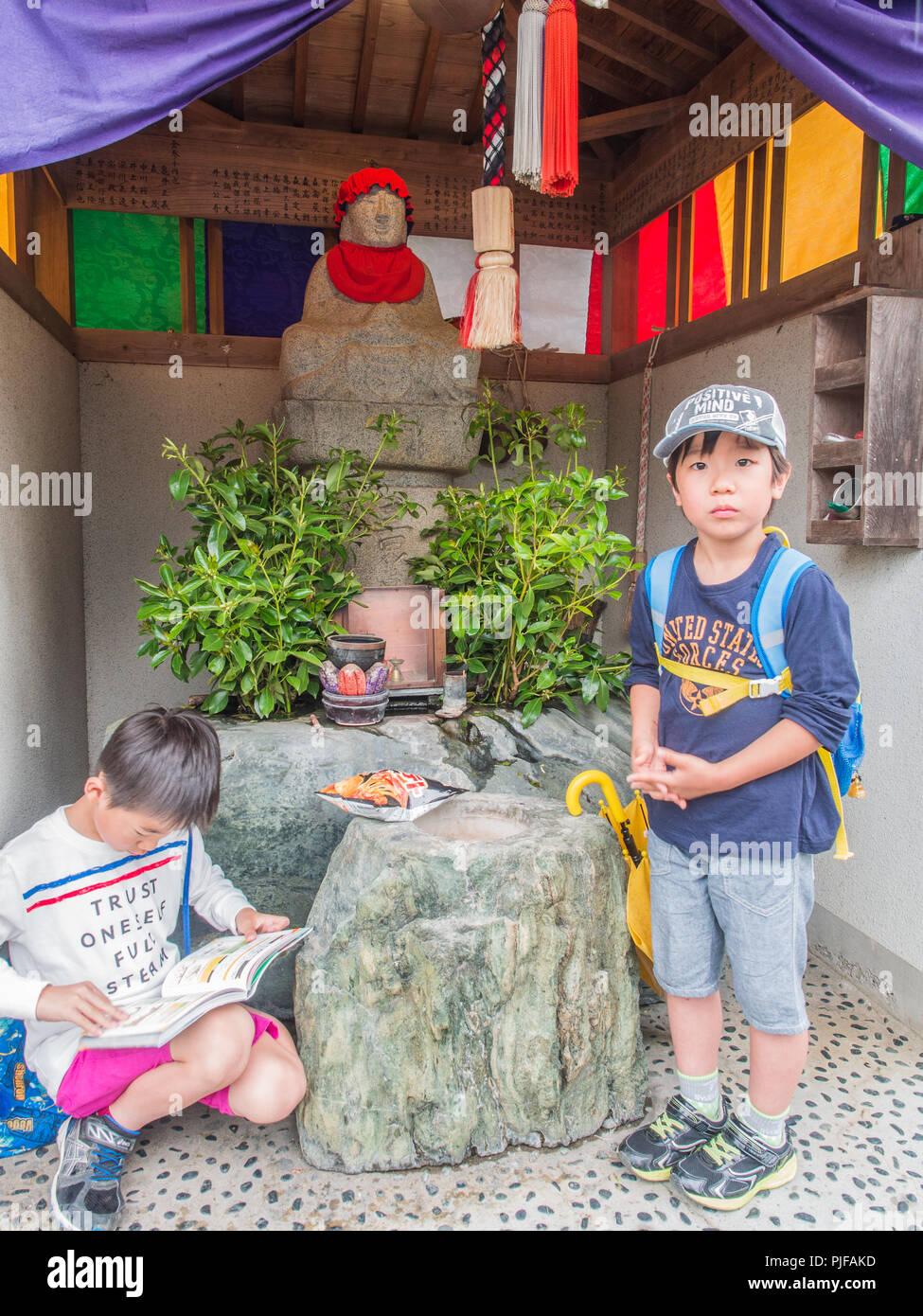2 boys shelter from rain in roadside shrine, henro no michi trail, Shikoku 88 temple pilgrimage, Stock Photo