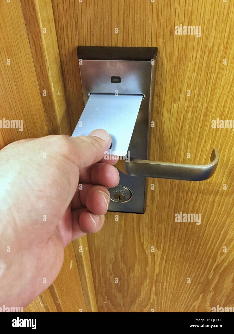 A POV of a human hand using a hotel or motel key card in a room door lock Stock Photo