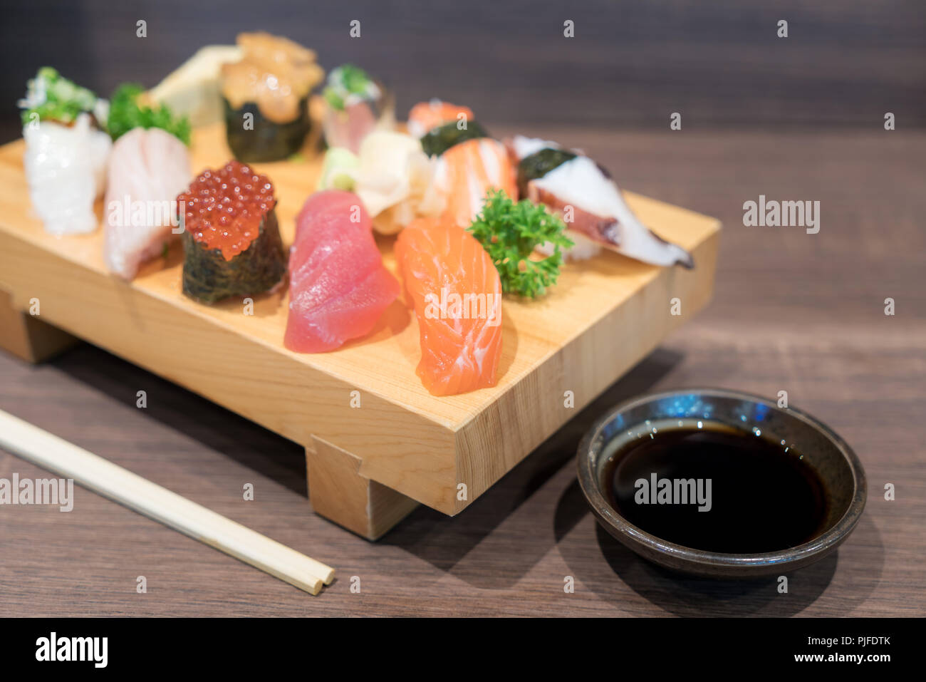 Close-up sushi and sashimi mixed on wooden plate on black wooden table. Japanese food. Stock Photo