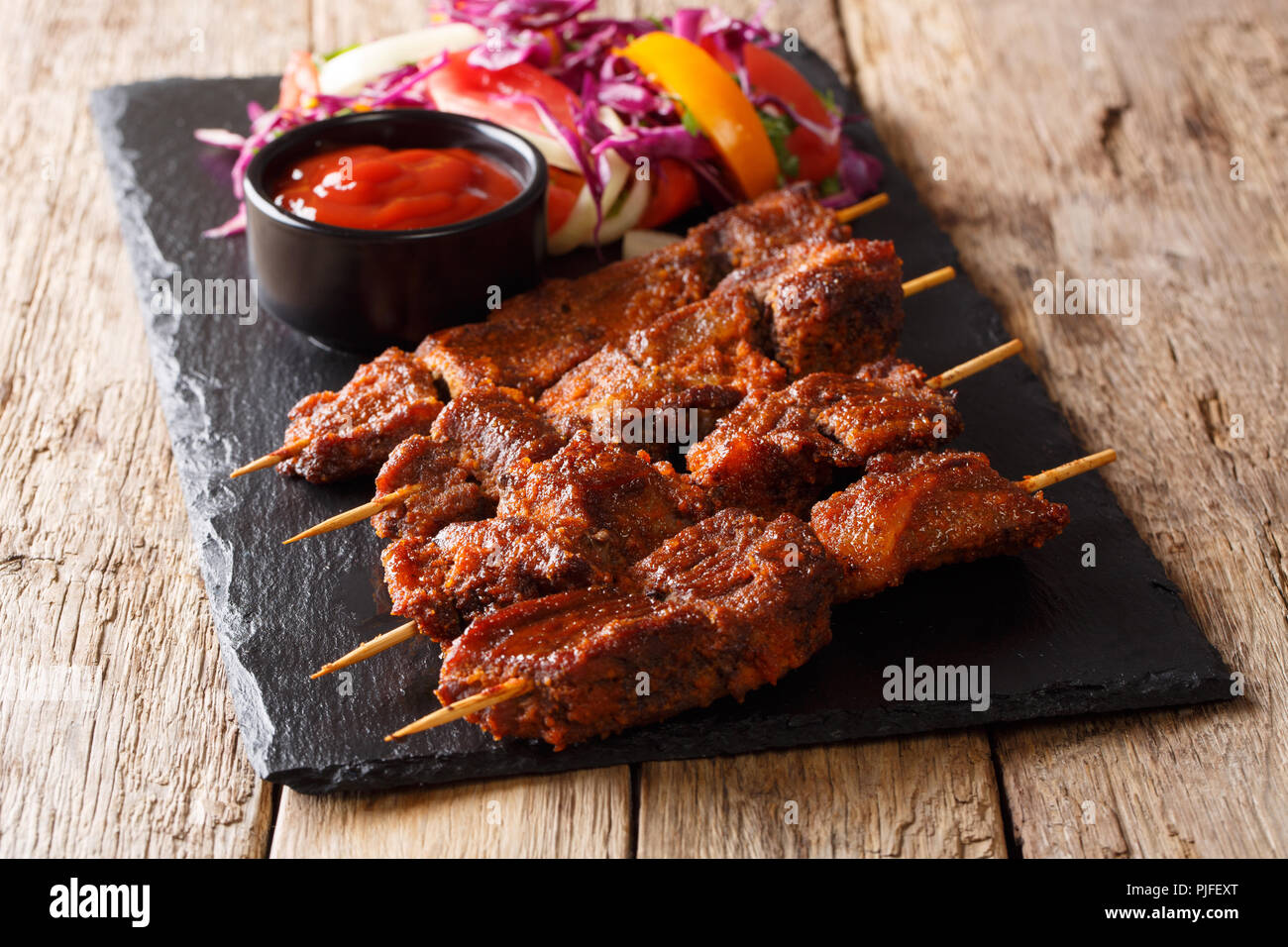suya kebab with ground peanuts and spices with fresh vegetable salad and ketchup close-up on the table. horizontal Stock Photo
