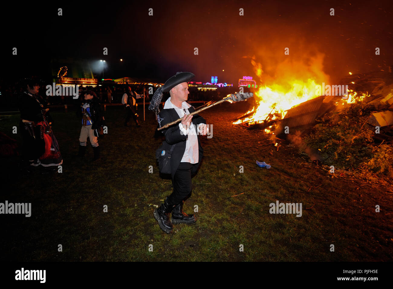 Bonfire night celebrations in Littlehampton, West Sussex, England, UK. A man throws a flaming torch onto a large bonfire. Stock Photo