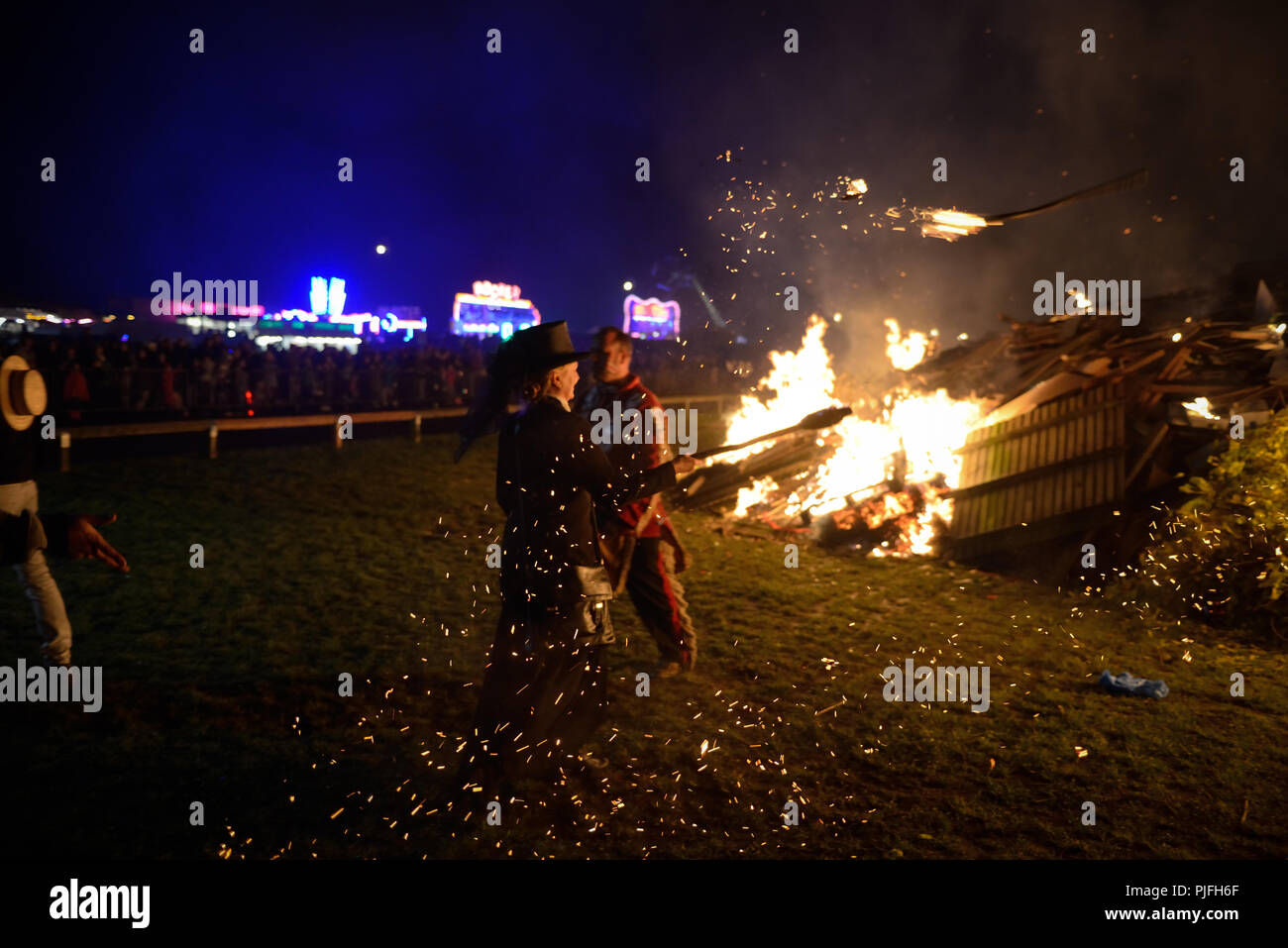 People ignite a bonfire by throwing lit flaming torches on to it during the Bonfire Night celebrations on November 5th in Littlehampton, West Sussex. Stock Photo