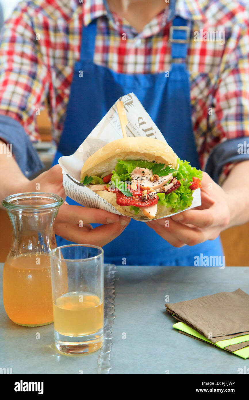 Man holding a Pan bagnat sandwich with chicken and lettuce. Healthy sandwich Stock Photo
