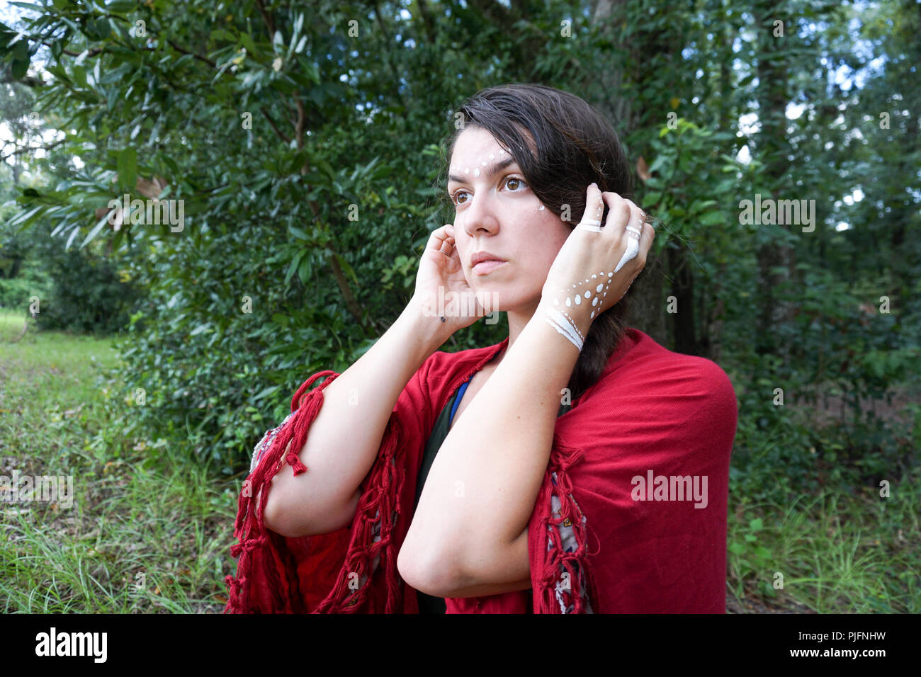 Young hippie beautiful brunette woman model with long braid hair white tribal makeup looking far away in the distance Stock Photo