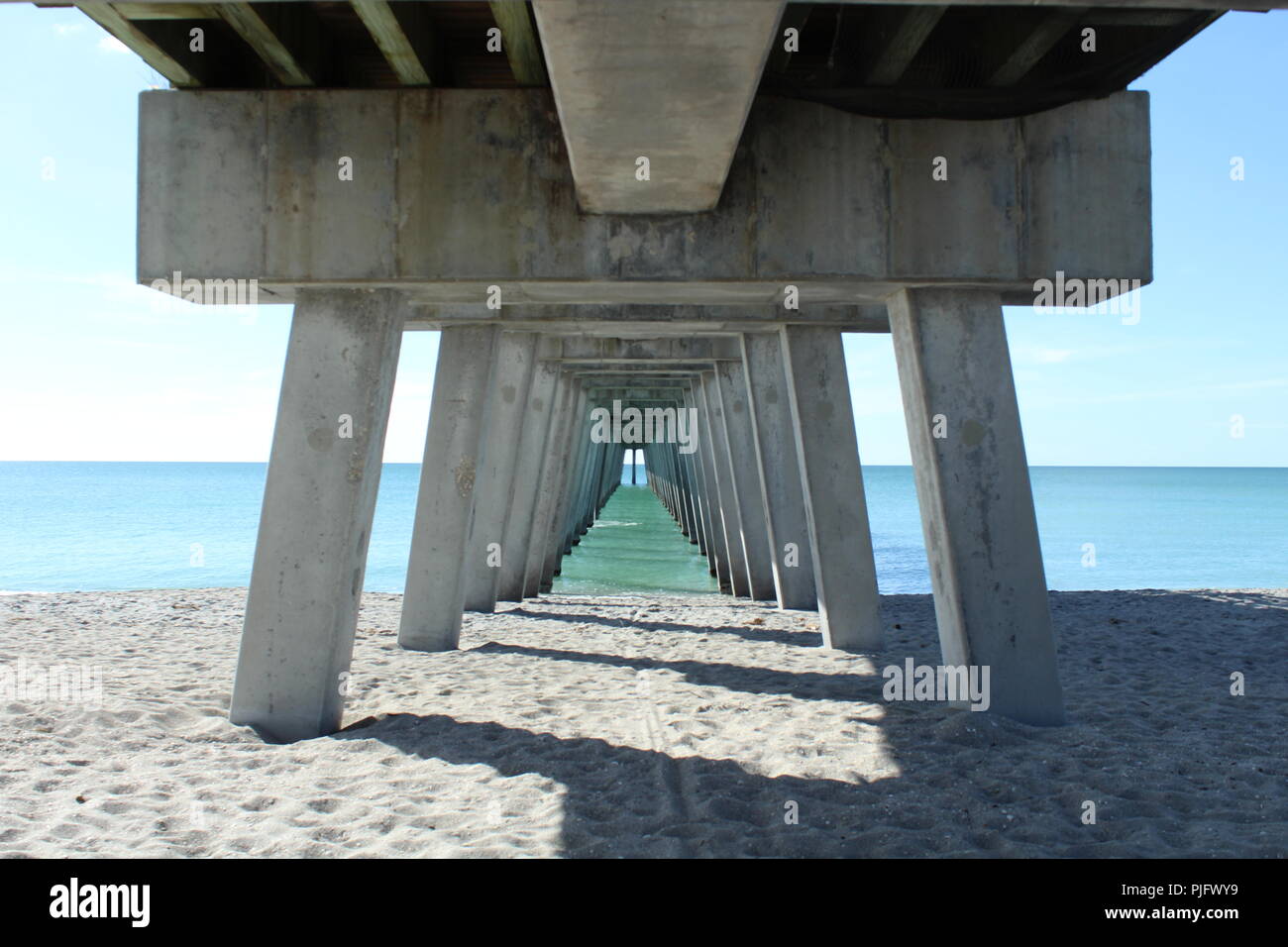 underneath a fishing pier on a sunny day on the ocean Stock Photo