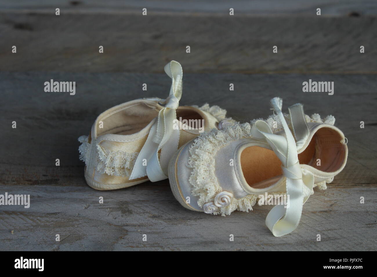 vintage baby shoes with ruffles and flowers on a natural wooden background Stock Photo