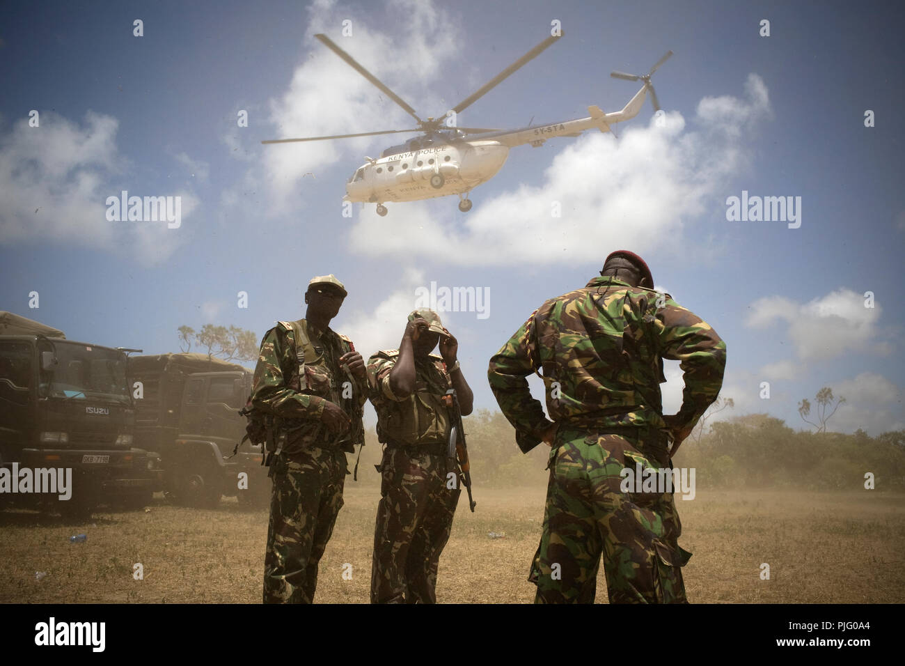 Kenyan security personnel shields from the wind of a lifting helicopter close to the Kenyan coast, September 20, 2012. Stock Photo