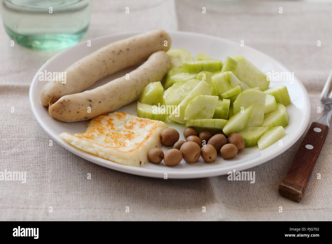 White sausages with roasted halloumi cheese, cucumbers, and olives Stock Photo