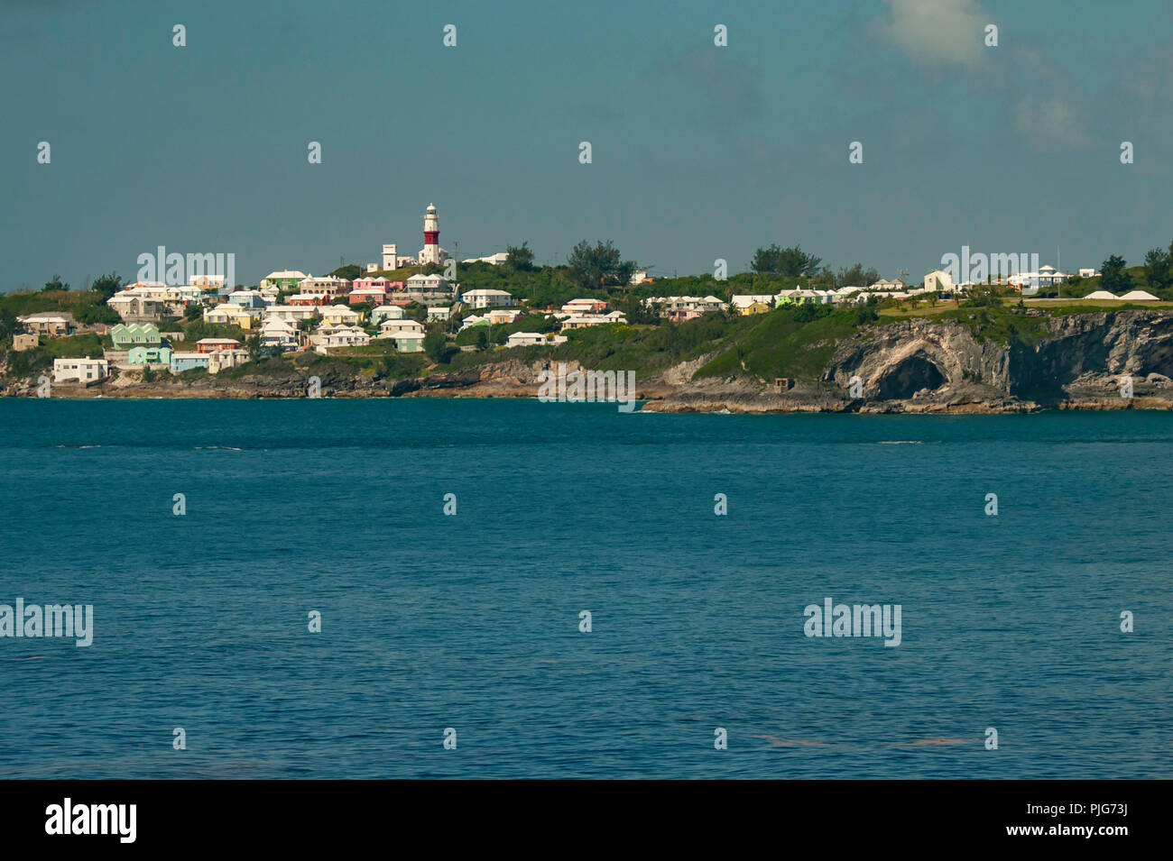 St. David's Bermuda - the St. Davids lighthouse / town / and seawall ( sea wall ) as viewed from a cruise ship heading to the port of King's Wharf Stock Photo