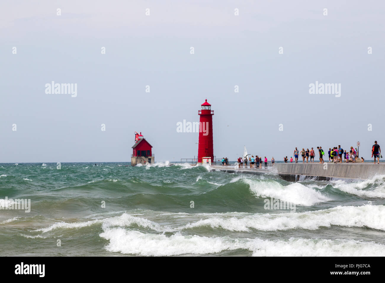 Tourists on a pier in south Haven Michigan on a day of rough waves on Lake Michigan. Grand Haven lighthouse. Stock Photo
