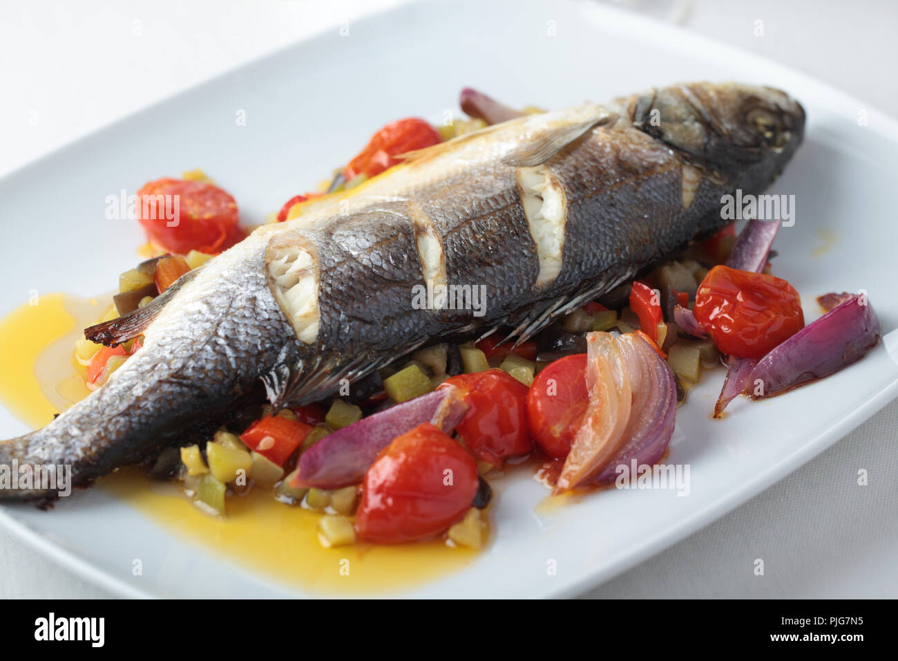 Baked sea bass with vegetables on a rectangular dish Stock Photo Alamy