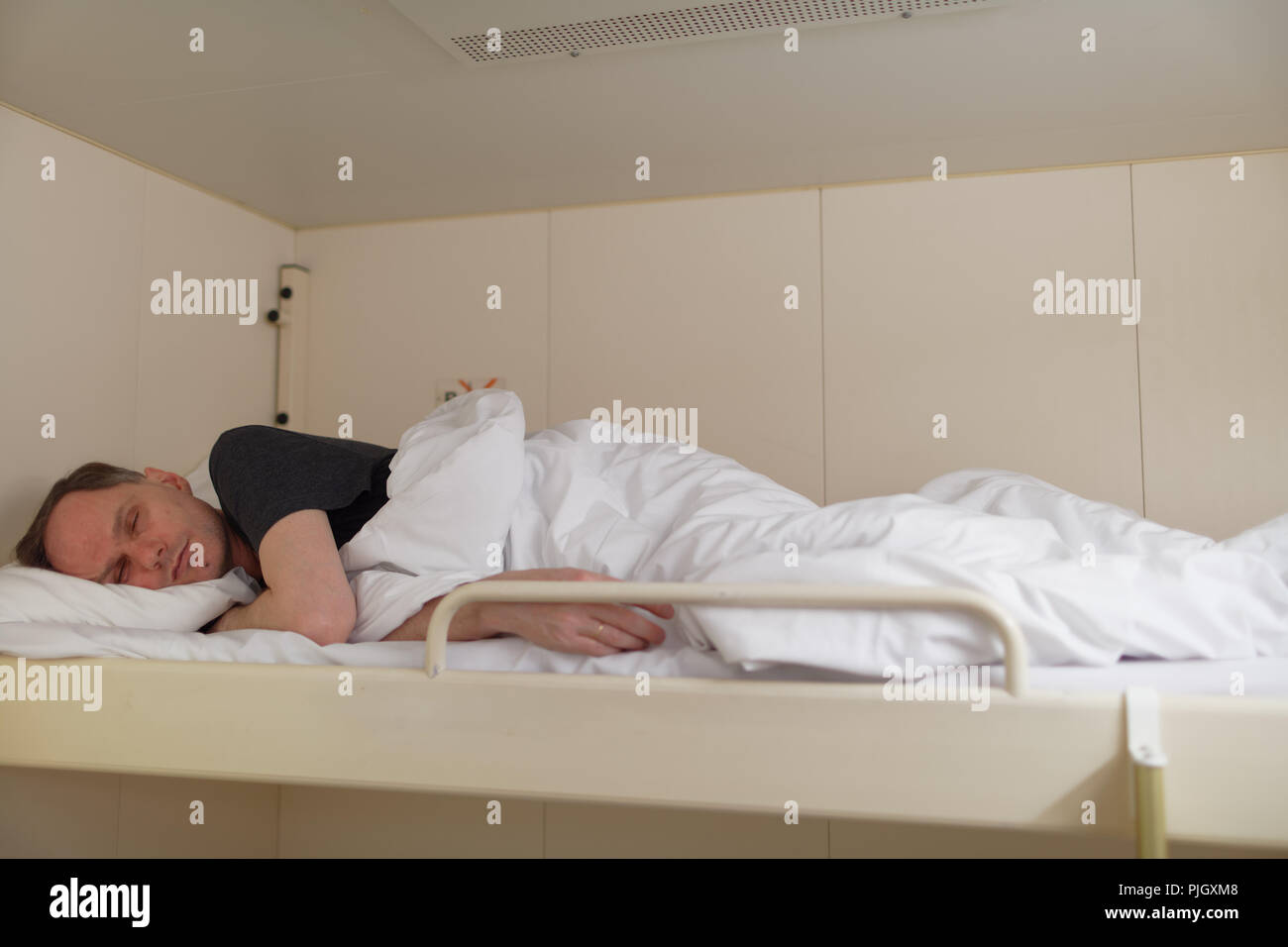 Man sleeping on upper berth in a cabin of a cruise ship Stock Photo