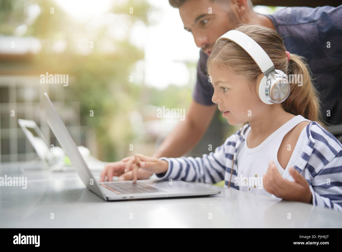 Little girl using laptop with help of daddy Stock Photo - Alamy
