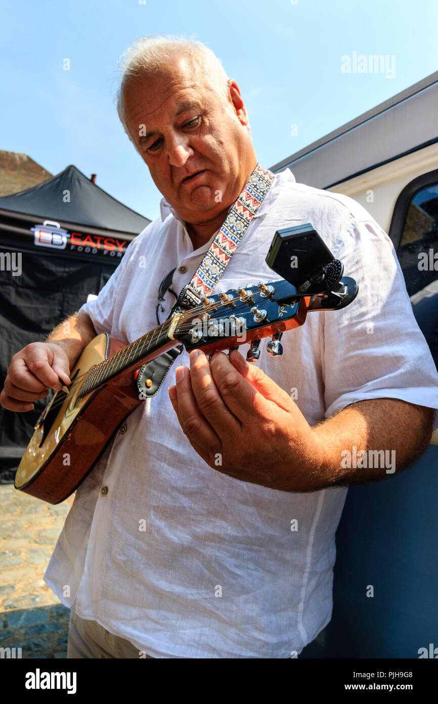 Mature man, caucasian, Peter Brooker, from the group 'Swinging the Lead'  turning his mandolin outdoors before going on stage Stock Photo - Alamy