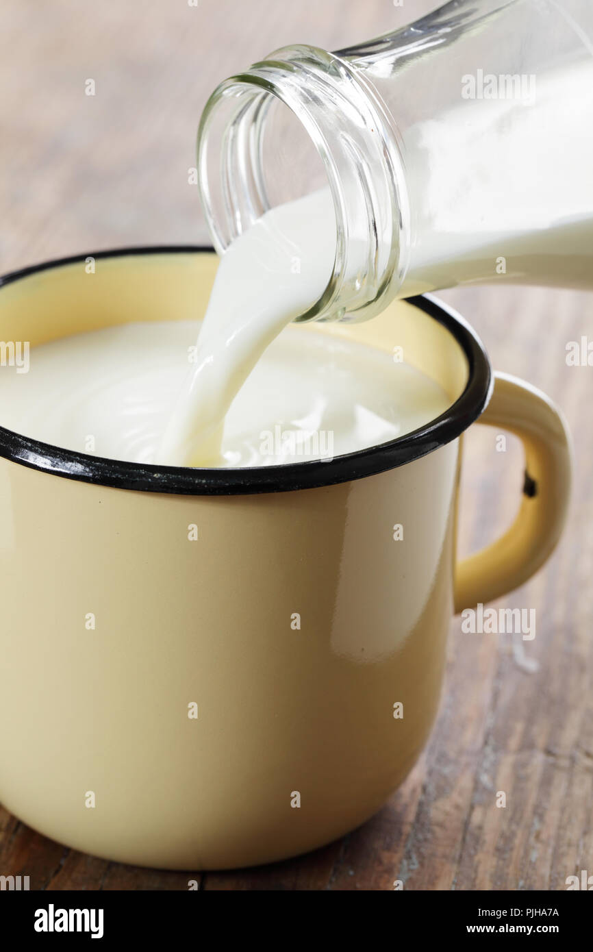Pouring milk into the rustic enamel mug Stock Photo