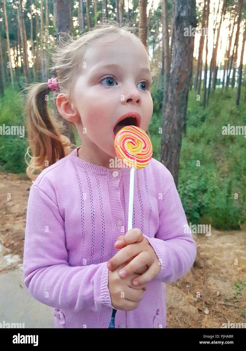 Candy Eating Funny child with candy lollipop, happy little girl eating big sugar ...
