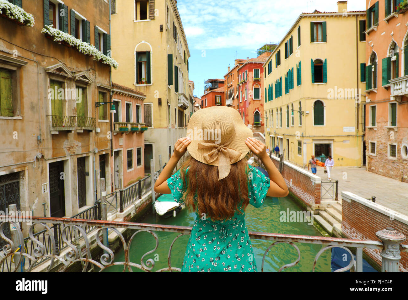 Sweet romantic girl charmed by Venice landscape. Rear view of female tourist on a bridge in Venice, Italy. Stock Photo